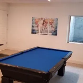 Blue pool table in a room with a world map art piece and a window.