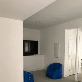 White room with a TV, blue beanbag chairs, and a closed white door.