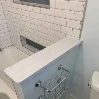 Bathroom with a white tiled shower, built-in shelf, and chrome shower caddy.