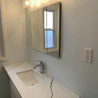 Bathroom with white countertop, sink, mirror cabinet, and faucet. Electrical outlet on wall.