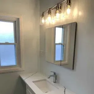 Bathroom with a window, vanity, mirror, and light fixture. The walls are light blue.