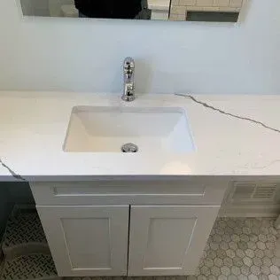 White bathroom vanity with a rectangular sink, faucet, and cabinet.