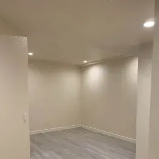 Empty room with recessed lighting and light-colored walls and floor, viewed from doorway.