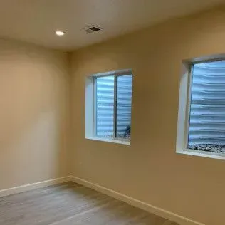 Empty room with two windows and beige walls.