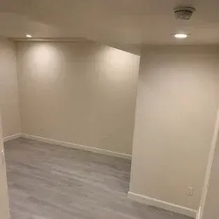 Empty room with gray flooring, cream walls, and recessed lighting.