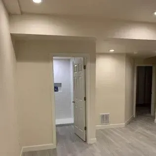 Empty interior with door opening to a laundry room and doorway leading to another room.