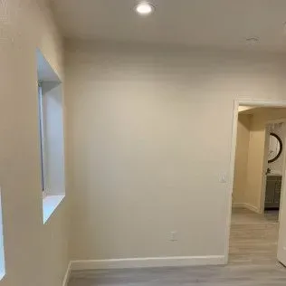 Interior view of a room with a window, doorway, and light-colored walls.