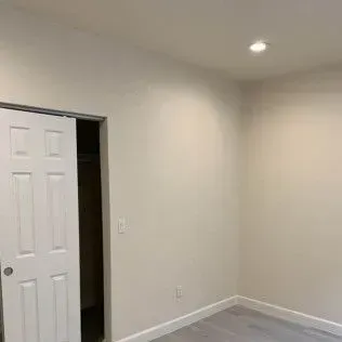 An empty, light-colored room with a sliding door to a closet on the left.