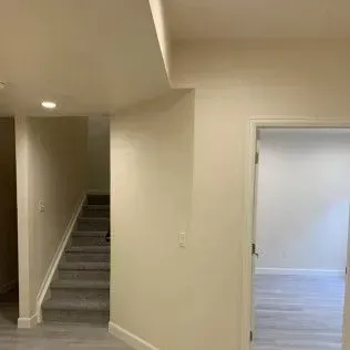 Interior view with stairs, doorway, beige walls, and white ceiling.