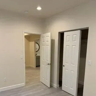 Interior view: Two white doors open to rooms. One leads to a bathroom with a mirror.