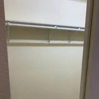 Empty white closet with a rod and shelf, seen from the doorway.