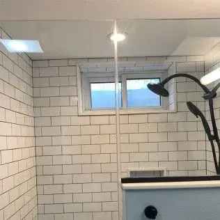 Shower with white subway tile, a window, and black shower fixtures.