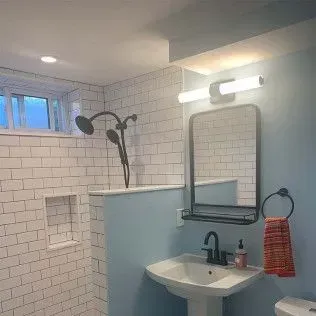 Bathroom with white subway tile shower, light blue walls, and a pedestal sink.