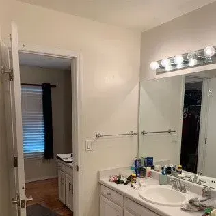 Bathroom interior with sink, mirror, and open doorway to a bedroom.