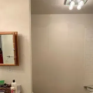 Bathroom interior with a mirror, light fixtures, and white walls.