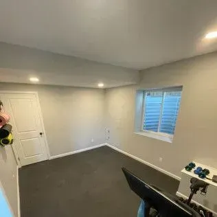 Home gym with exercise equipment, rubber floor, and a small window.