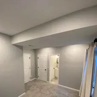 Empty room with gray walls, white doors, and a bathroom doorway.