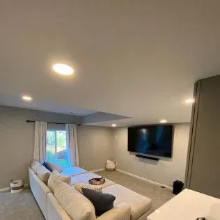 Living room with a large TV, sectional sofa, and recessed lighting.