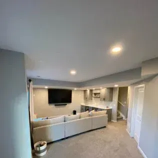 Living room with sectional sofa, TV, and small bar area. Gray walls and carpet.
