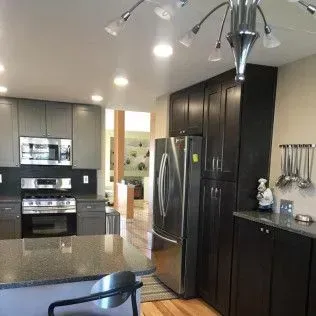 Kitchen with gray and dark brown cabinets, stainless steel appliances, and a granite countertop.