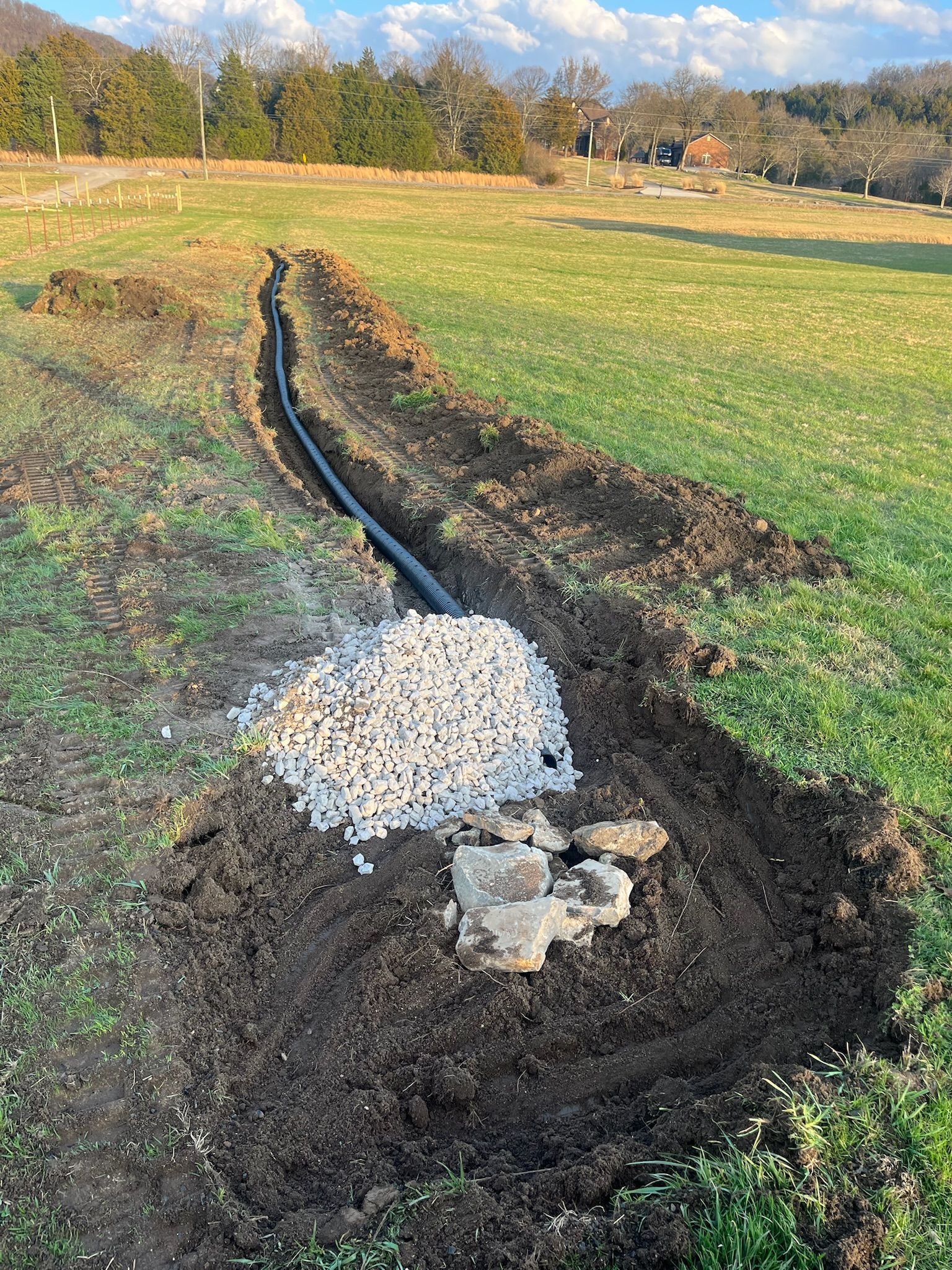 A pipe is being installed in the dirt in a field.