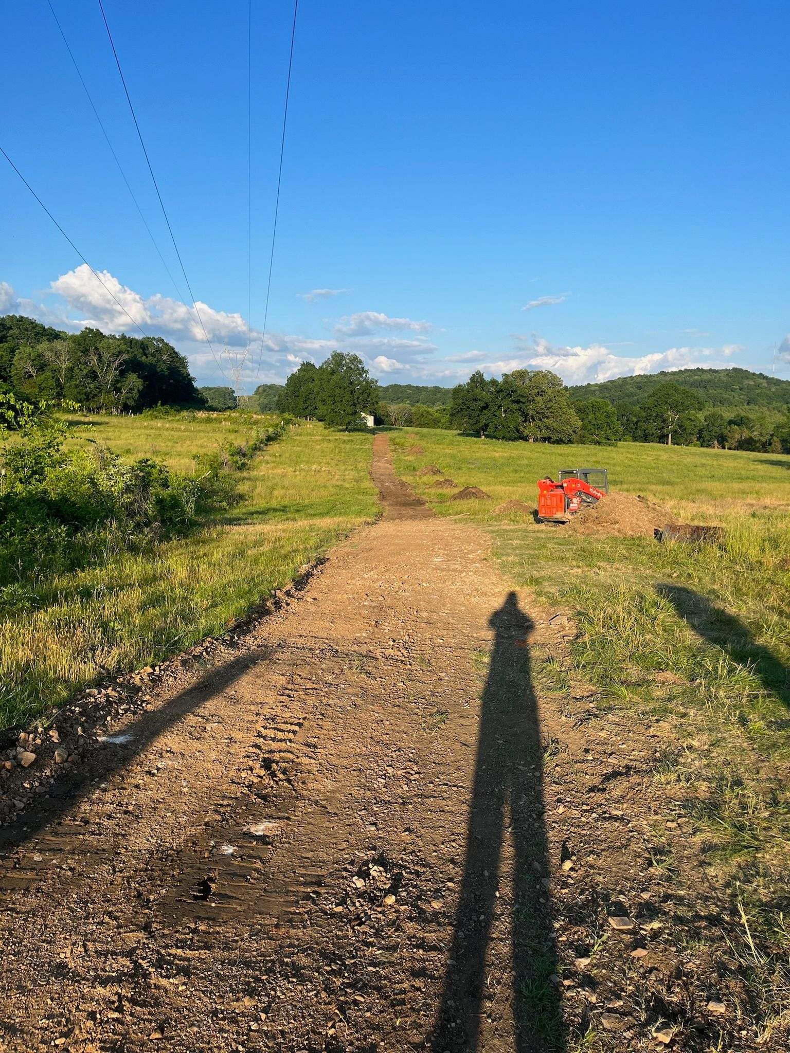 A person is walking down a dirt road in a field.