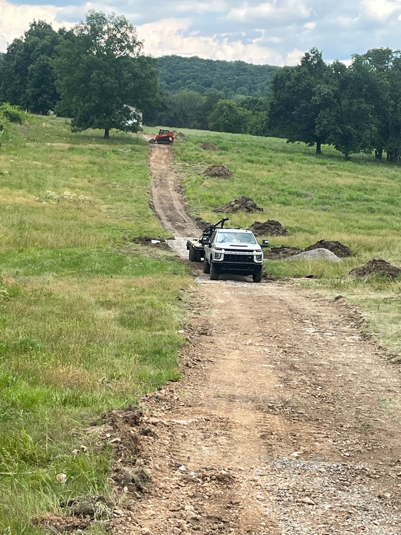 A car is driving down a dirt road in a field.