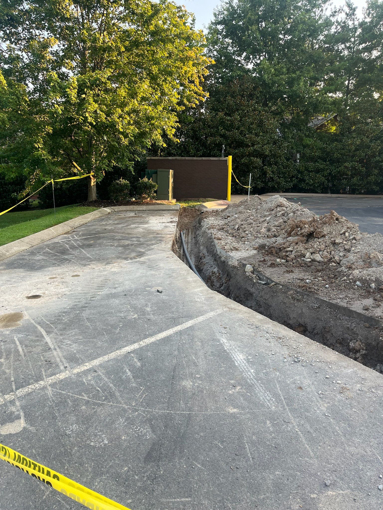 There is a large hole in the ground in the middle of a parking lot.