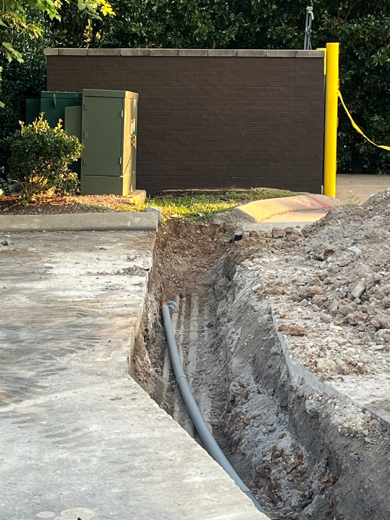 A pipe is being installed in the dirt next to a brick wall.