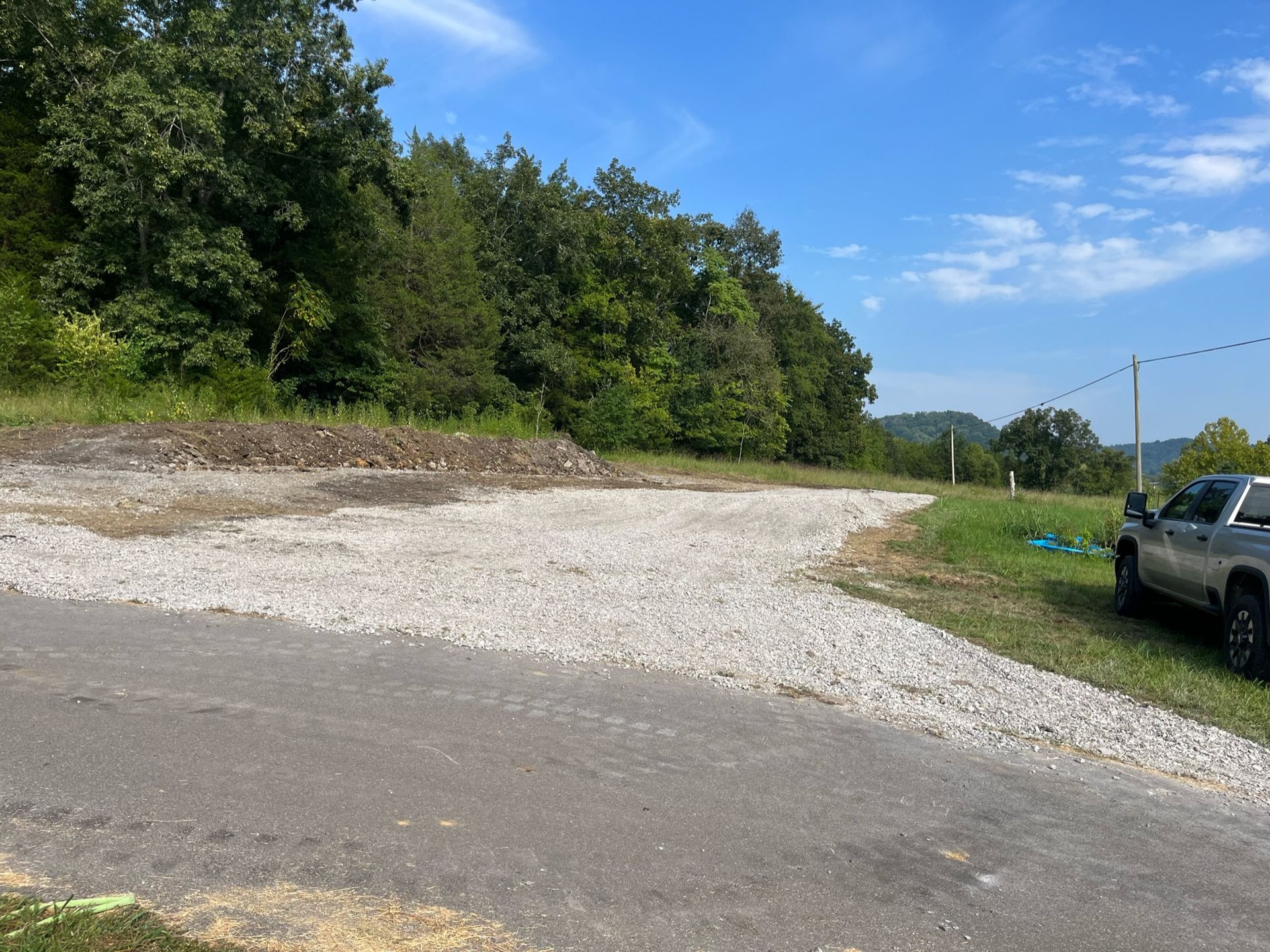 A truck is parked on the side of a gravel road.