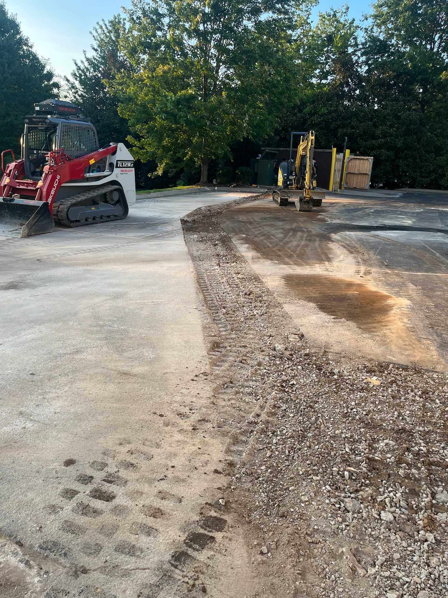 A bulldozer is driving down a gravel road next to a tractor.