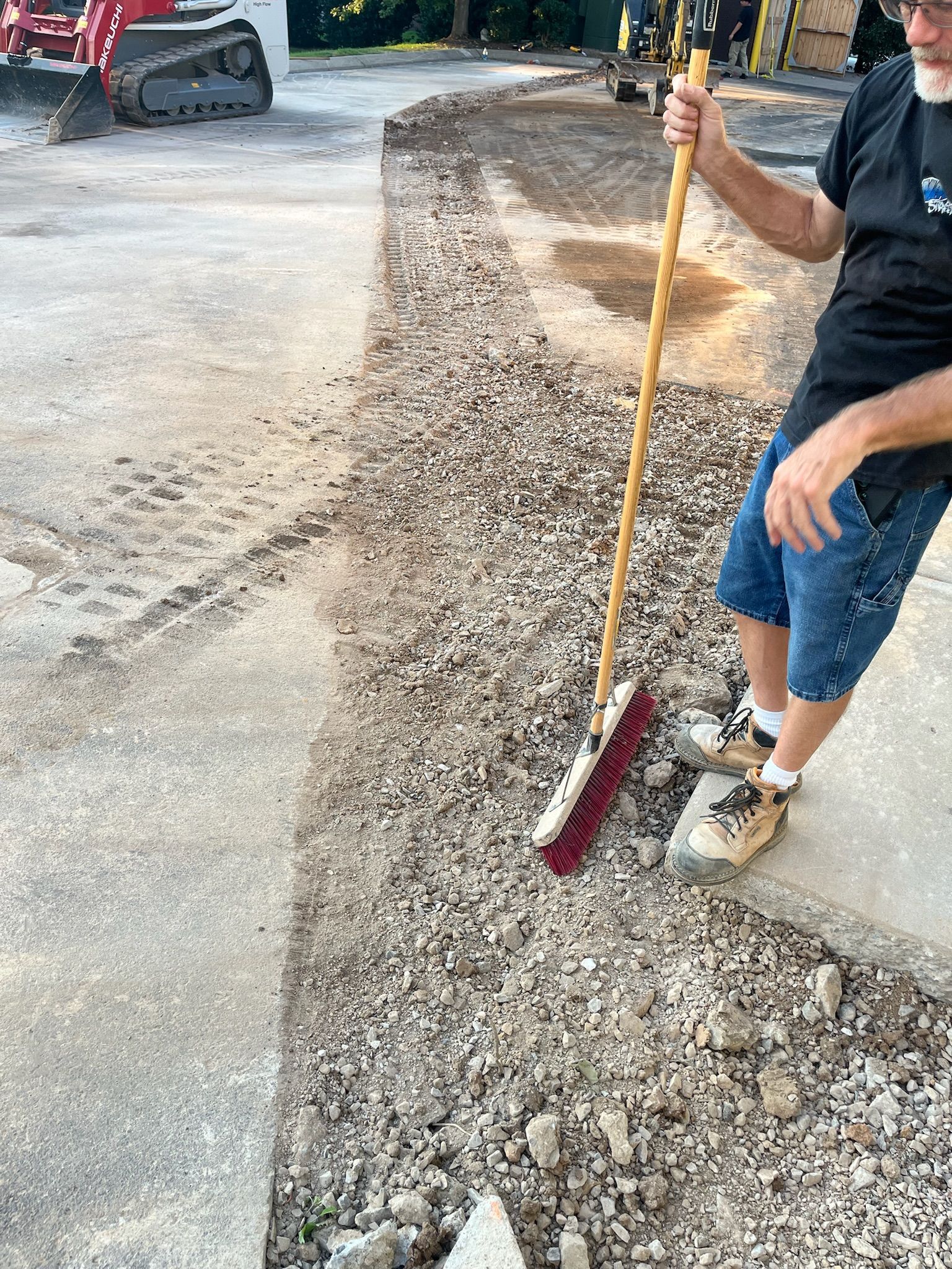 A man is sweeping gravel with a broom.