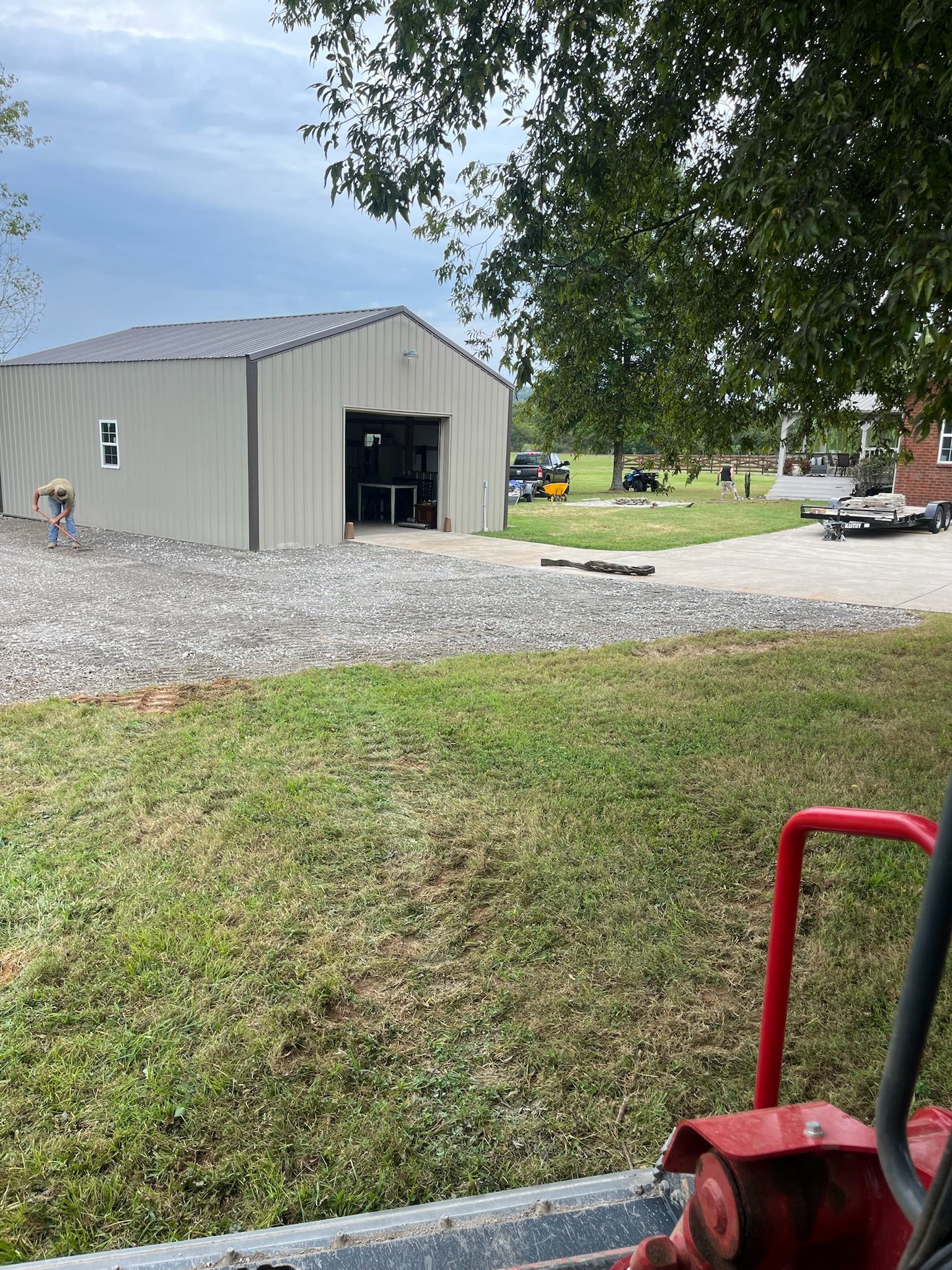 A red tractor is parked in front of a large building.