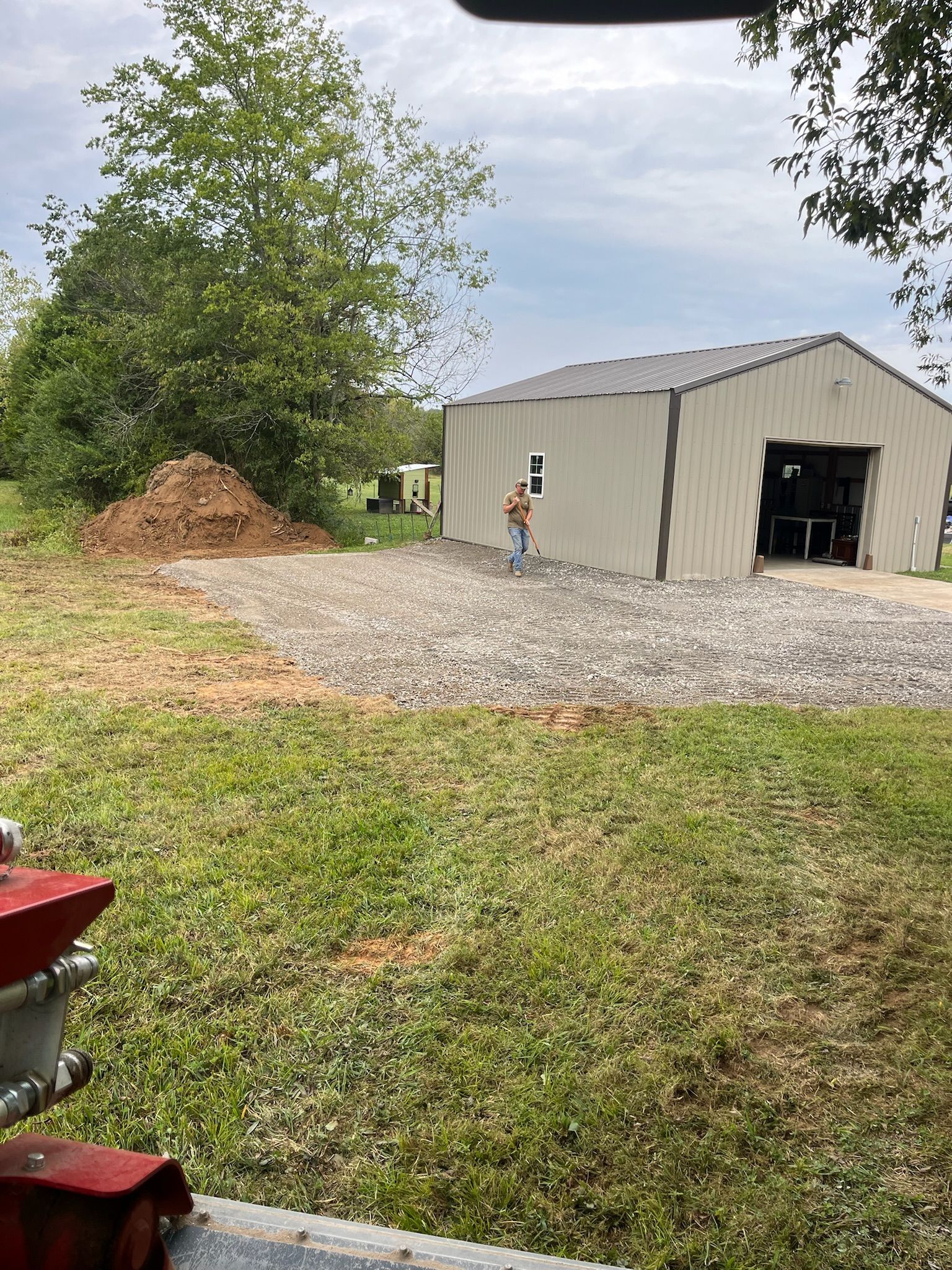 A man is standing in front of a building in a grassy field.