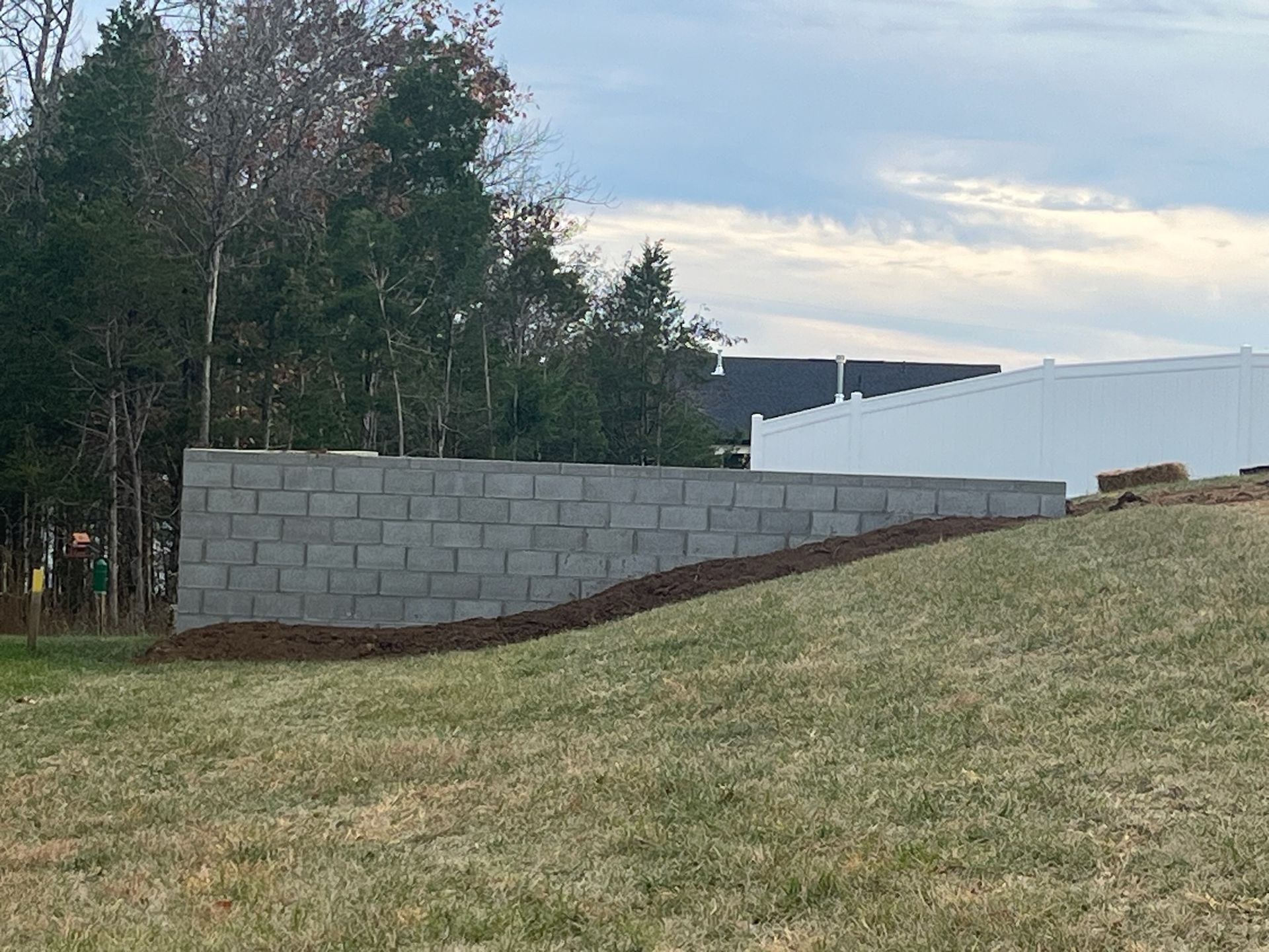A brick wall is being built in the middle of a grassy field.