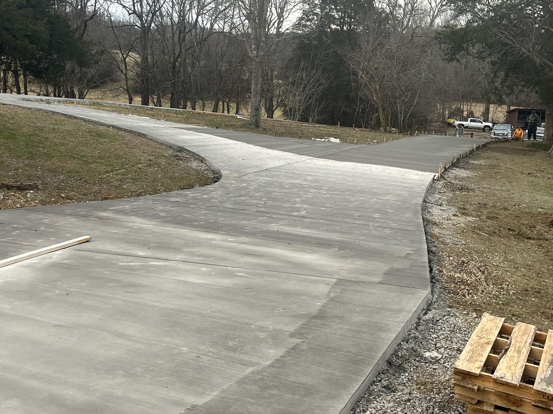A concrete driveway with a wooden pallet on the side of it.