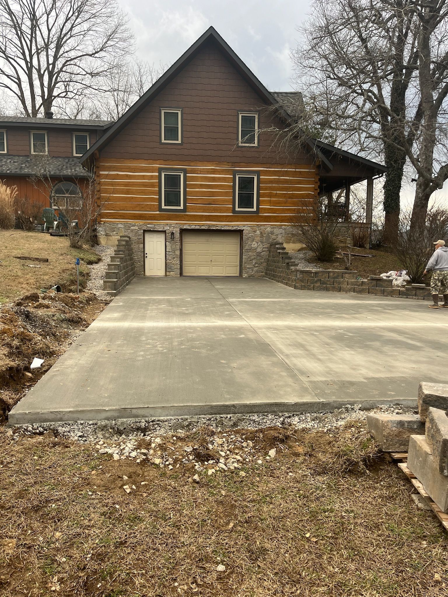 A log cabin with a concrete driveway in front of it.