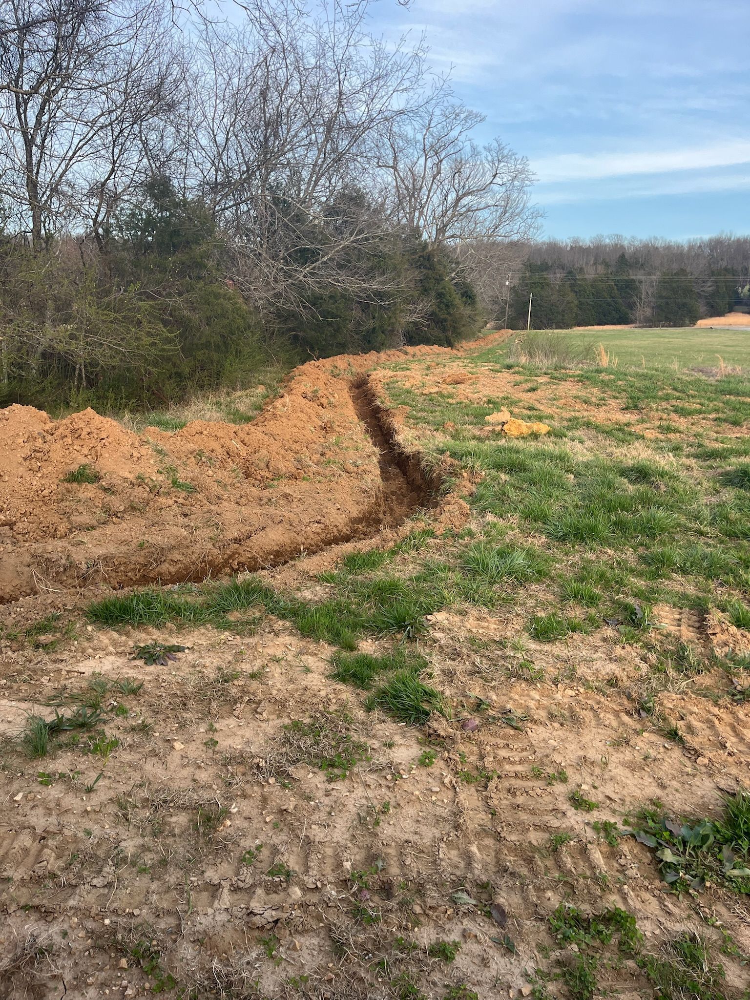 There is a large pile of dirt in the middle of a field.