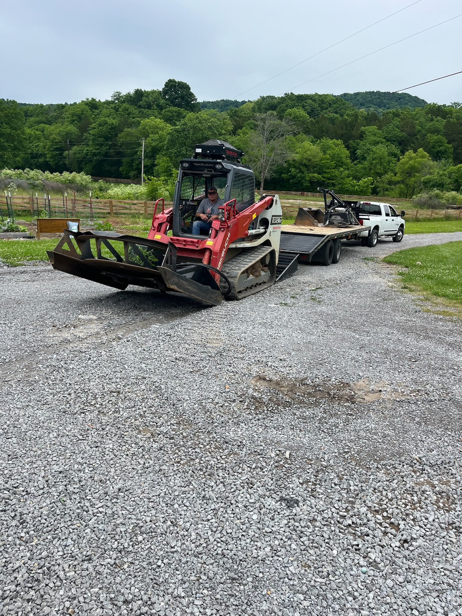 A bulldozer is being towed by a truck on a gravel road.