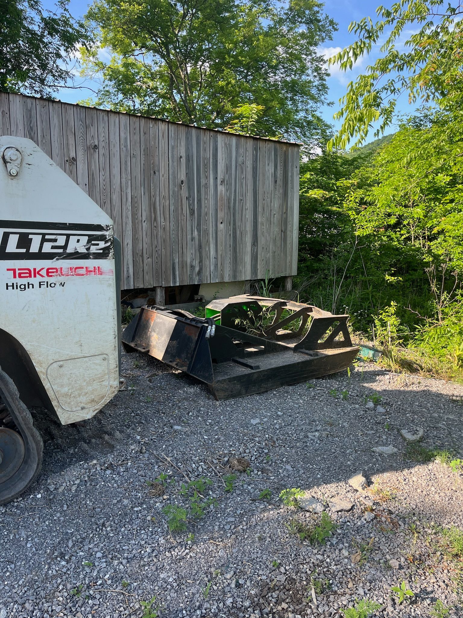 A white truck is parked in a gravel lot next to a wooden building.
