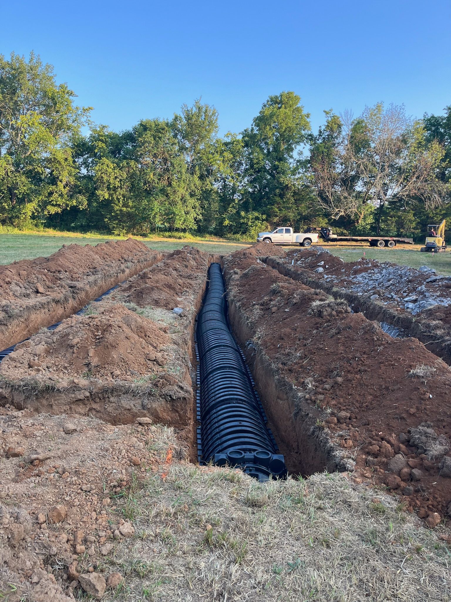 A large pipe is being installed in the dirt in a field.