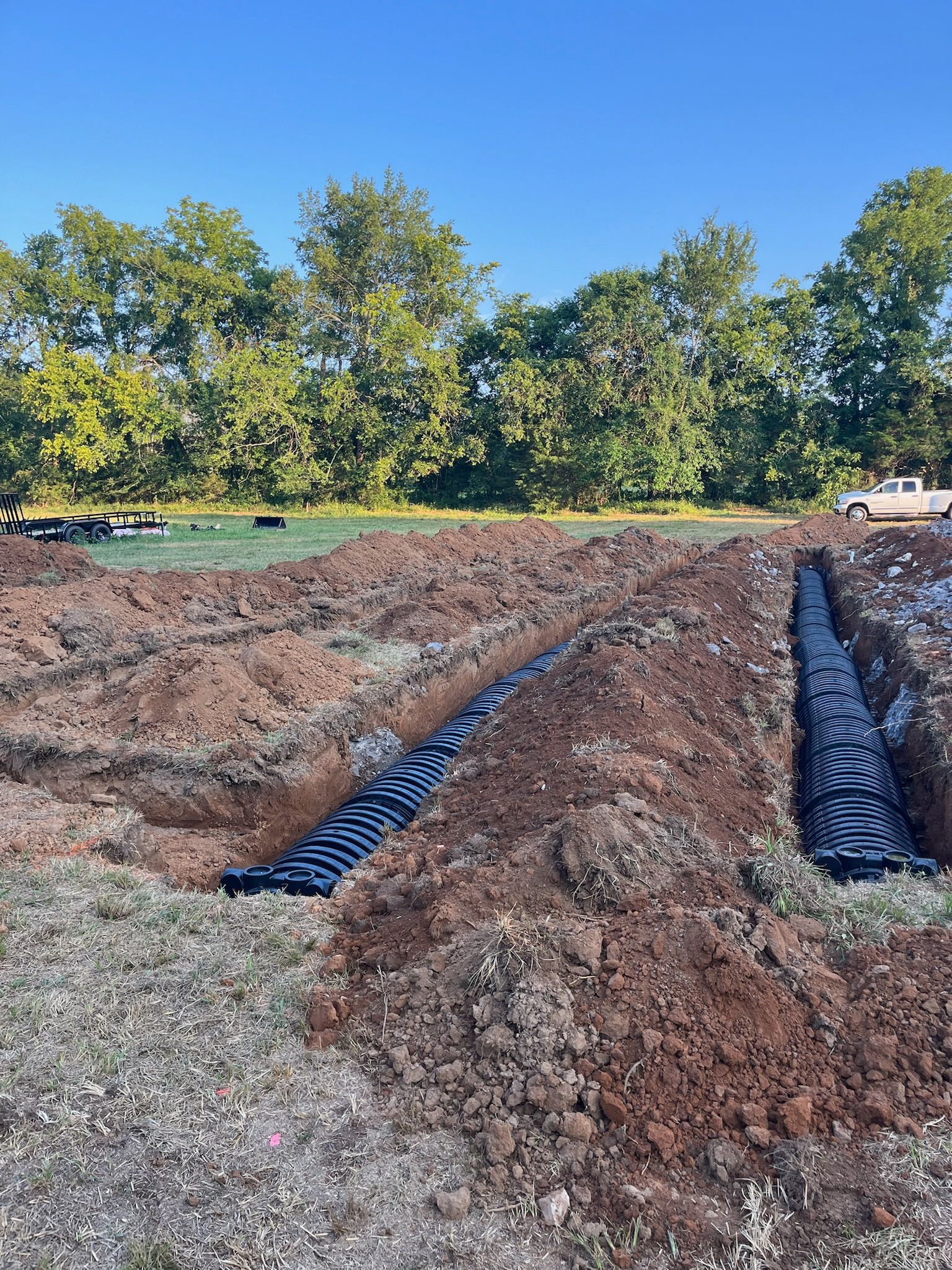 A drainage system is being installed in a dirt field.