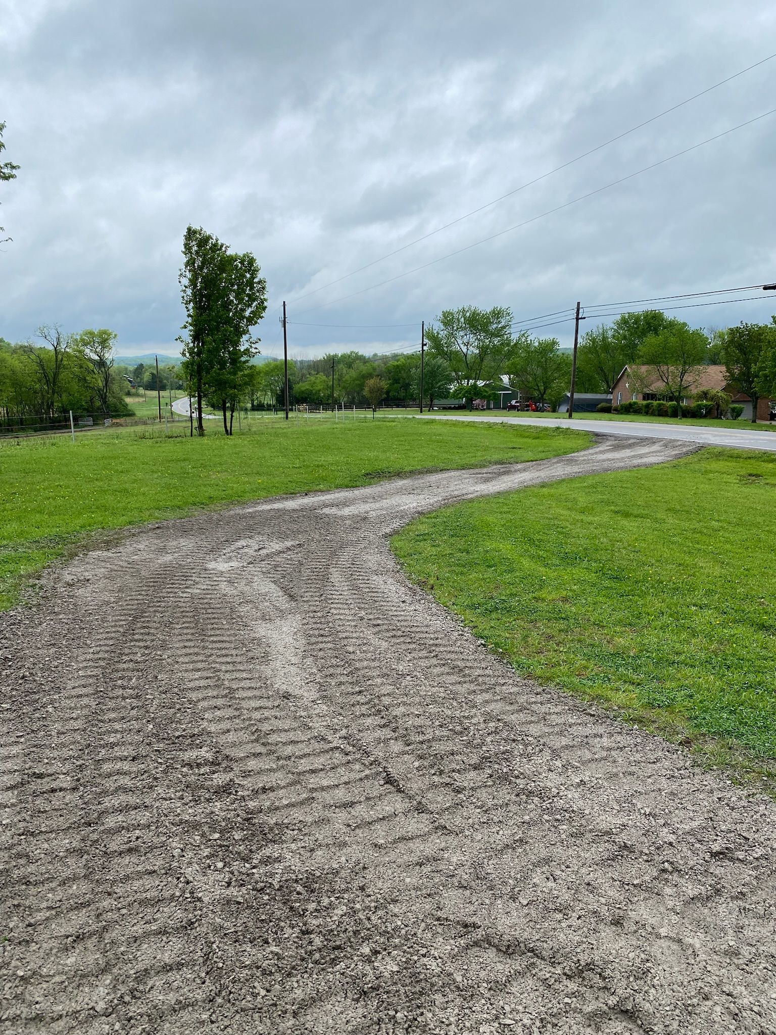There is a dirt path going through a grassy field.