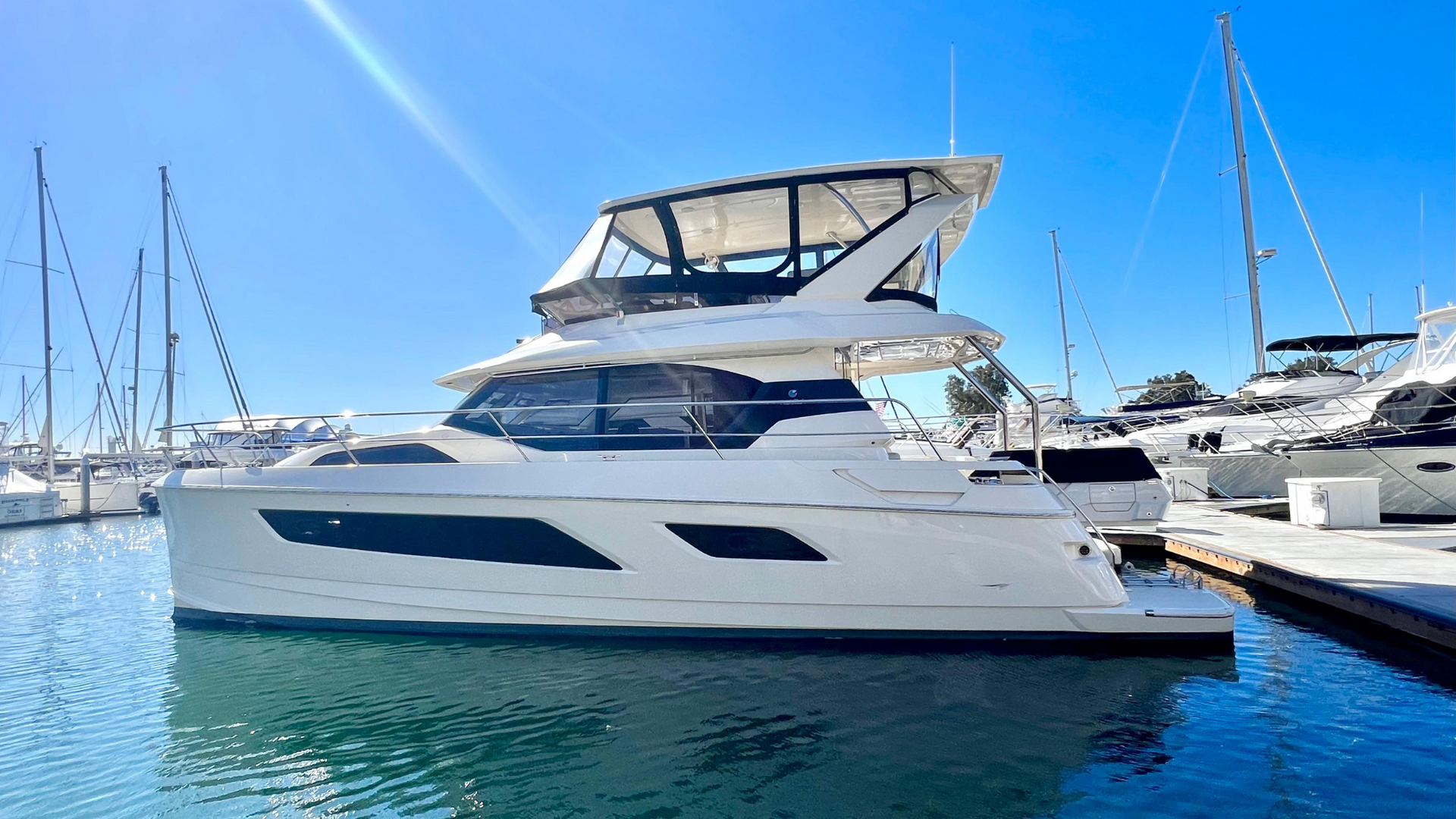 A large white yacht is docked in a marina.