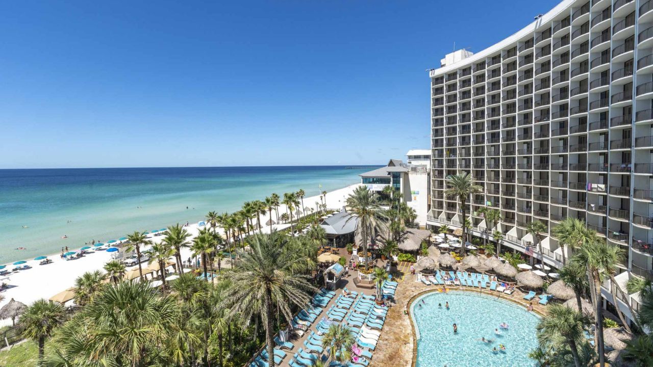 An aerial view of a large hotel with a swimming pool in front of it.