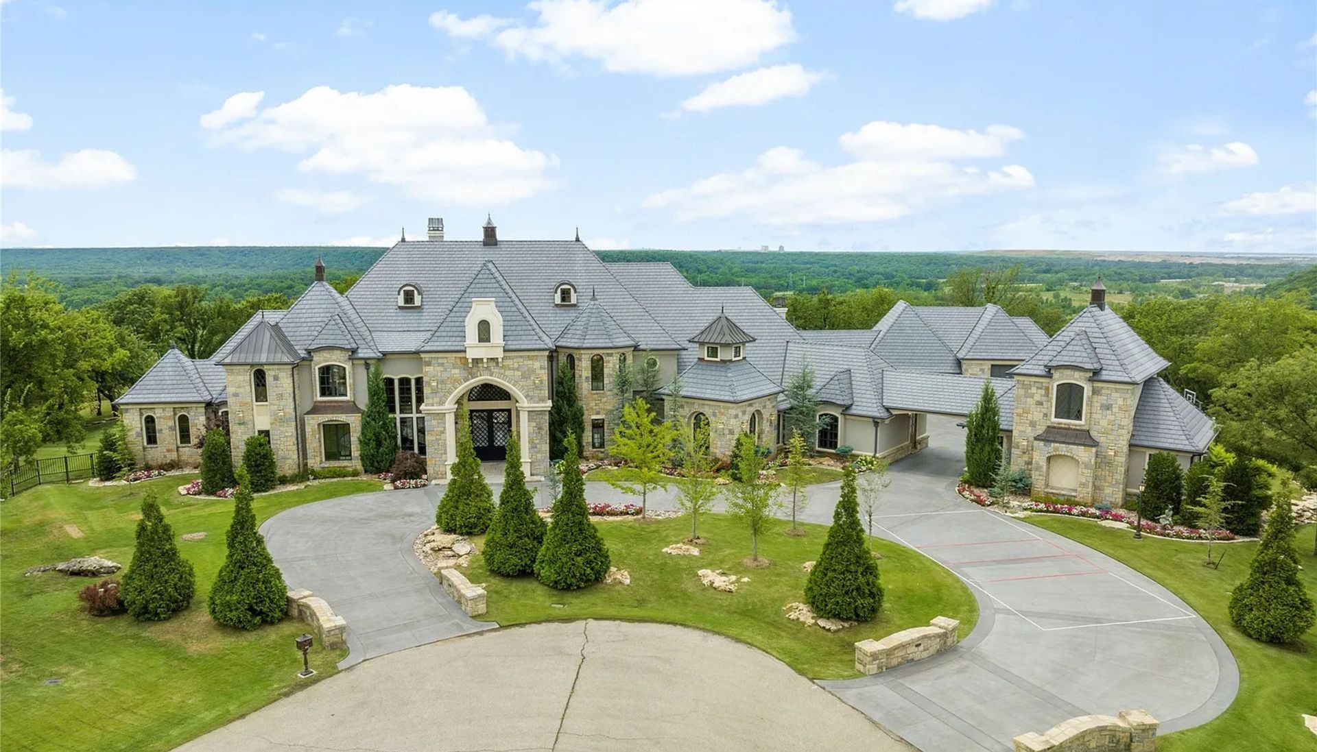 An aerial view of a large house with a large driveway leading to it.