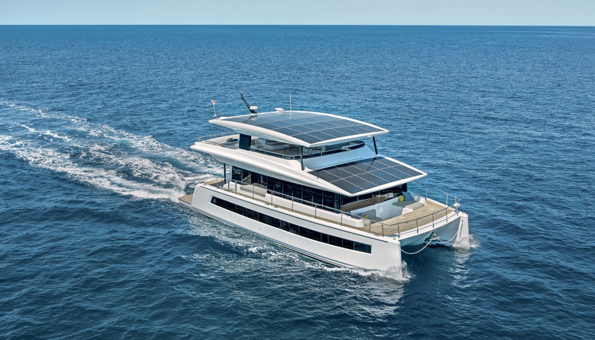 A large white boat with solar panels on the roof is floating on top of a large body of water.