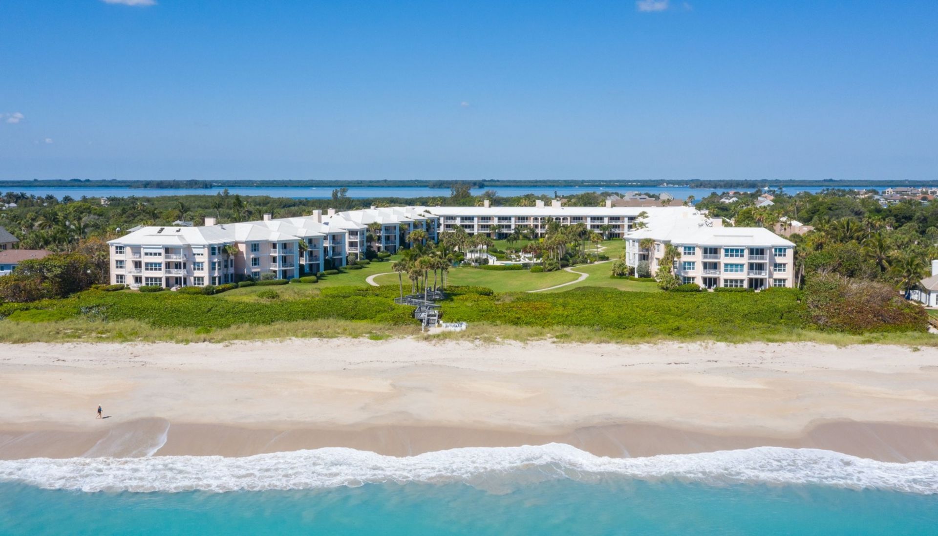 An aerial view of a large white building on a beach next to the ocean.