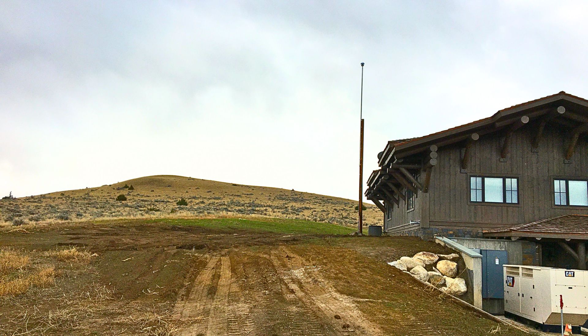 A house is sitting in the middle of a dirt field with a mountain in the background.