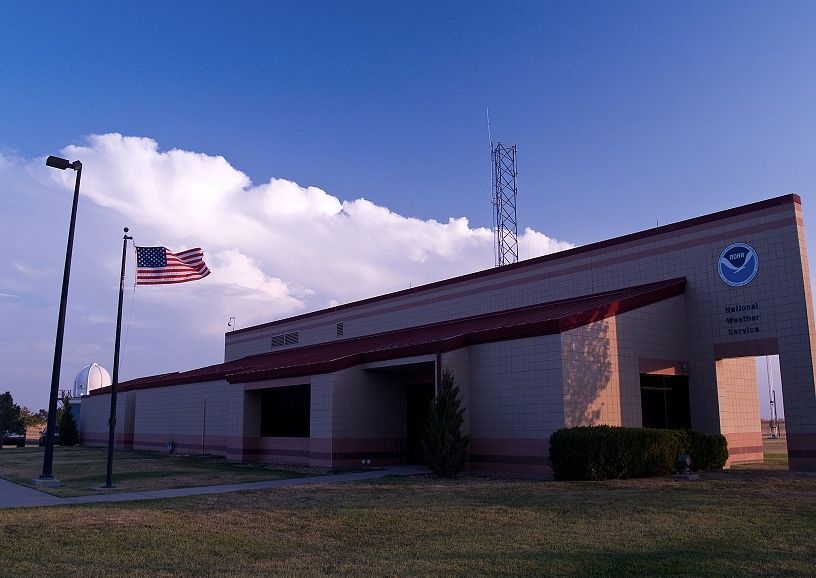 Two american flags are flying in front of a building